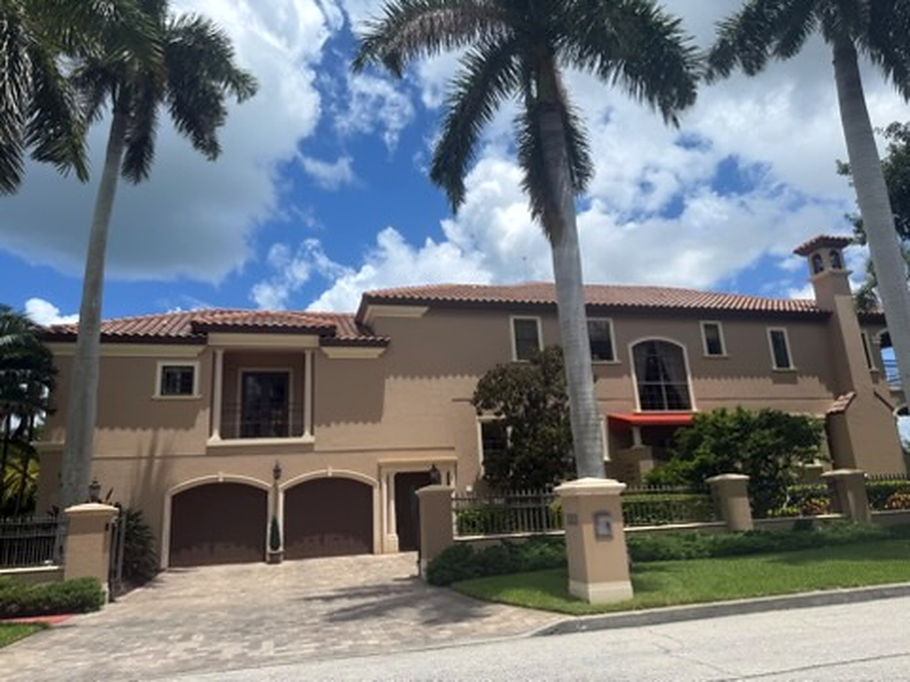Mediterranean home with paver driveway and manicured front landscaping