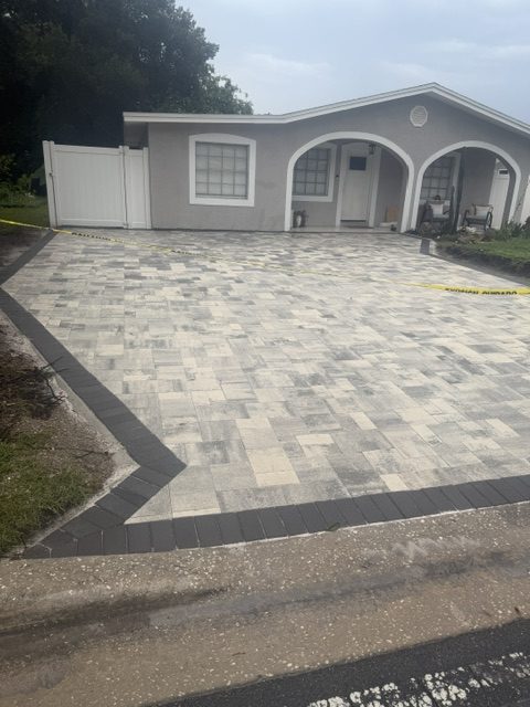 Wide paver driveway with contrasting border banding at a white home